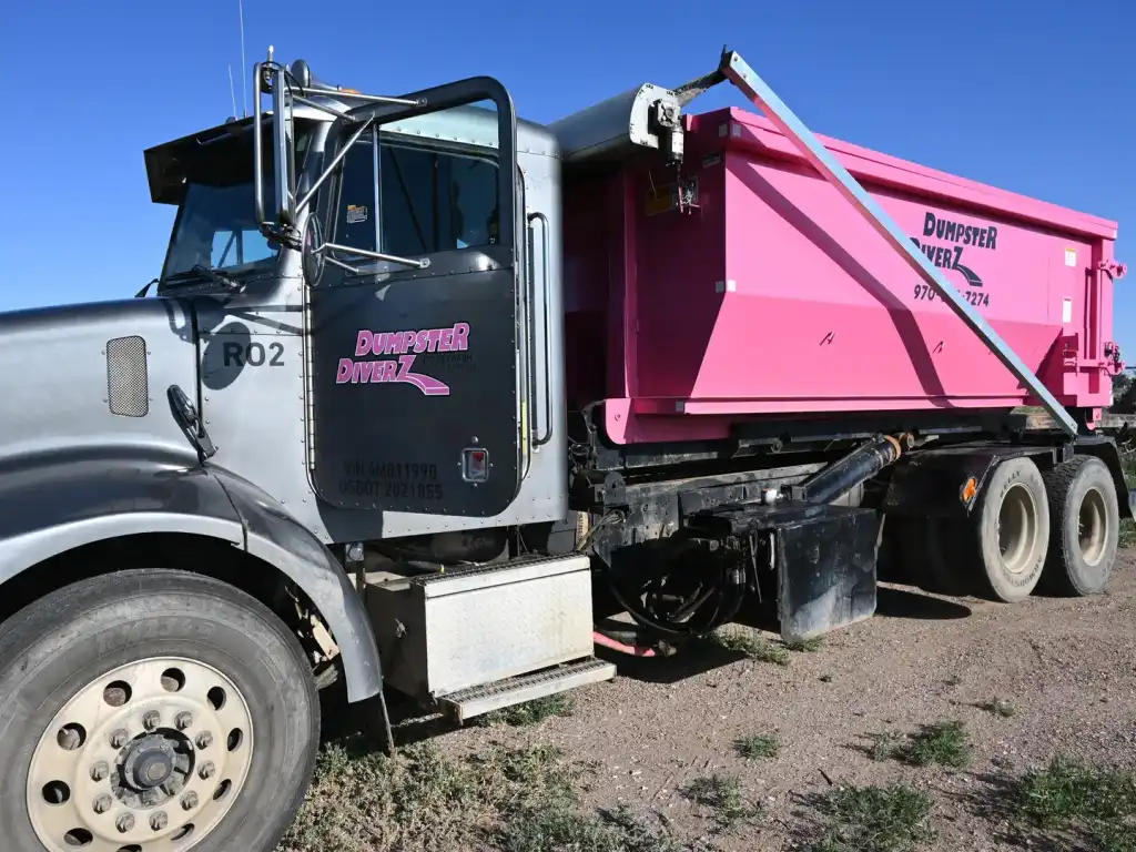 Dumpster Diverz pink garbage truck and bin curbside for residential trash pickup